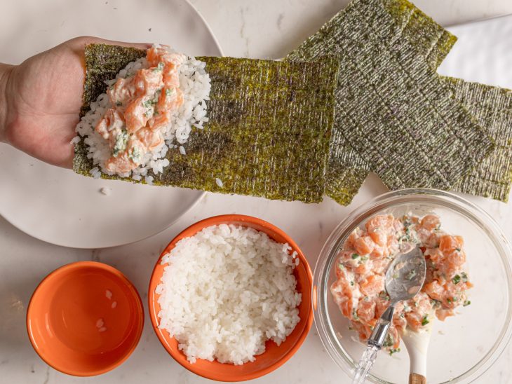 Folha de nori com salmão acomodado sobre o arroz.