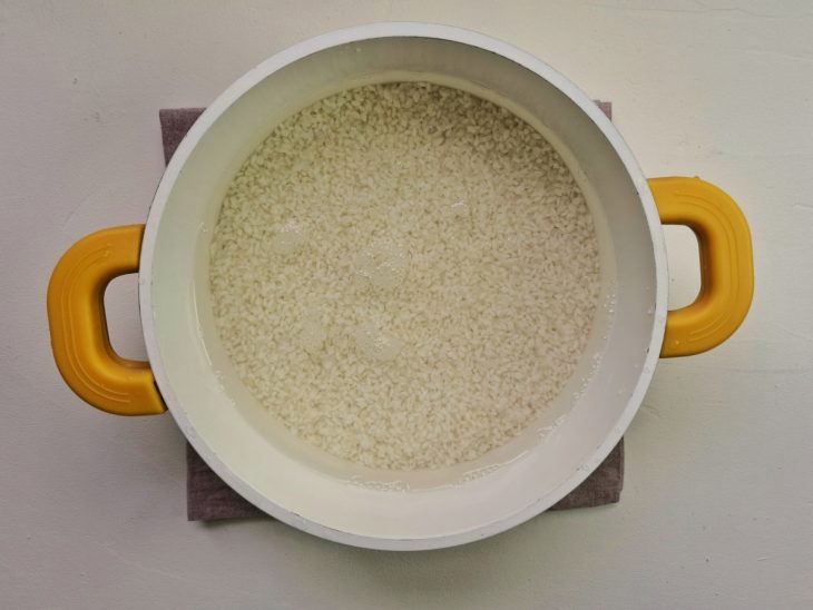 Uma panela com arroz lavado e hidratado.