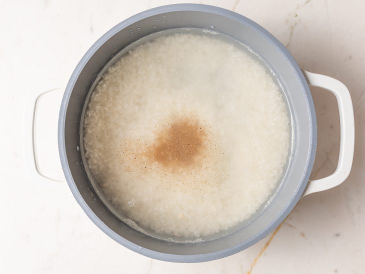 Uma panela com água, arroz e temperos.