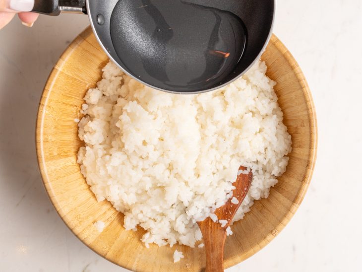 Uma tigela com o arroz sendo temperado com molho su.