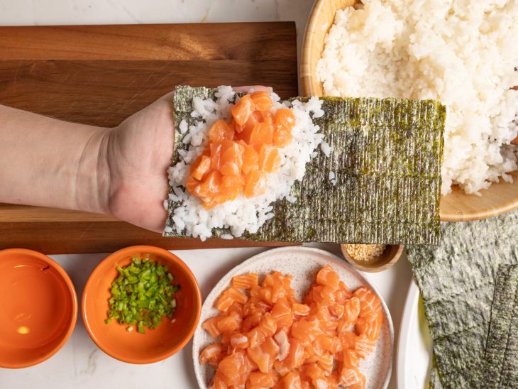 Porções de salmão e arroz colocadas sobre a alga.