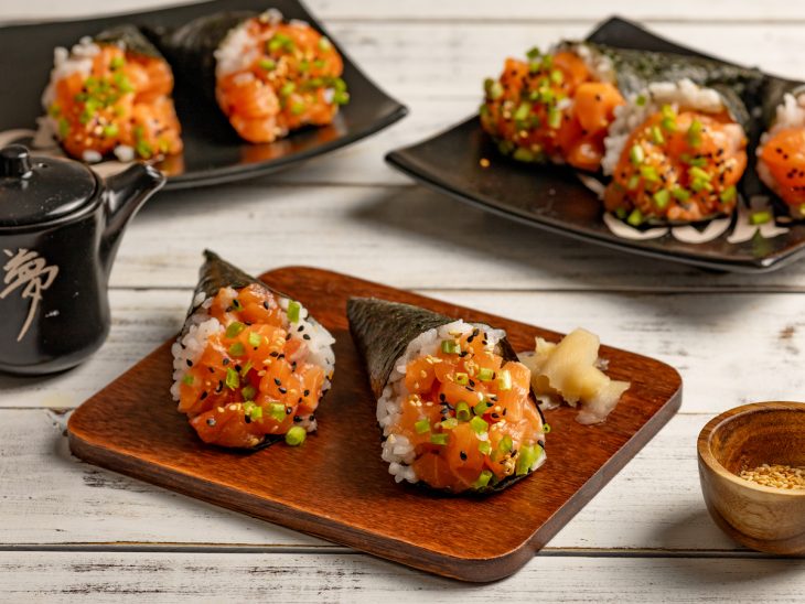 Tábua e pratos contendo temaki salmão.