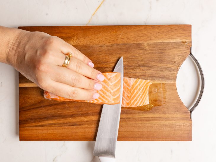 Uma tábua com salmão e a pele sendo retirada.