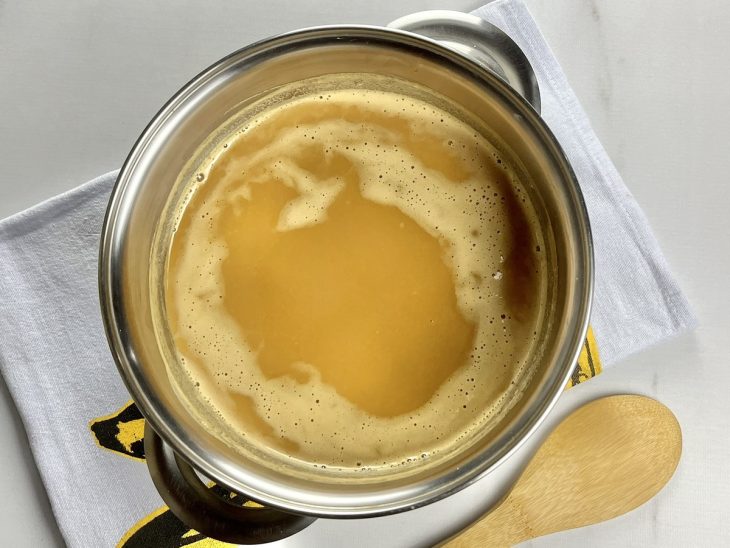 Uma panela contendo a mistura de caramelo, creme de leite com o soro, leite e eritritol.