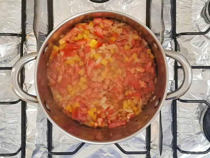 Uma panela ao fogo com azeite, cebola, alho, tomate, pimentão.