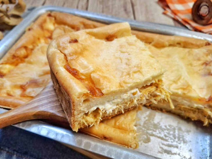 Torta de frango pronta para consumo com um pedaço cortado em evidência.