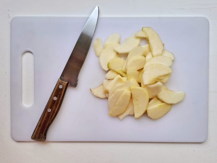 Uma faca e fatias de maçã sobre uma tábua.