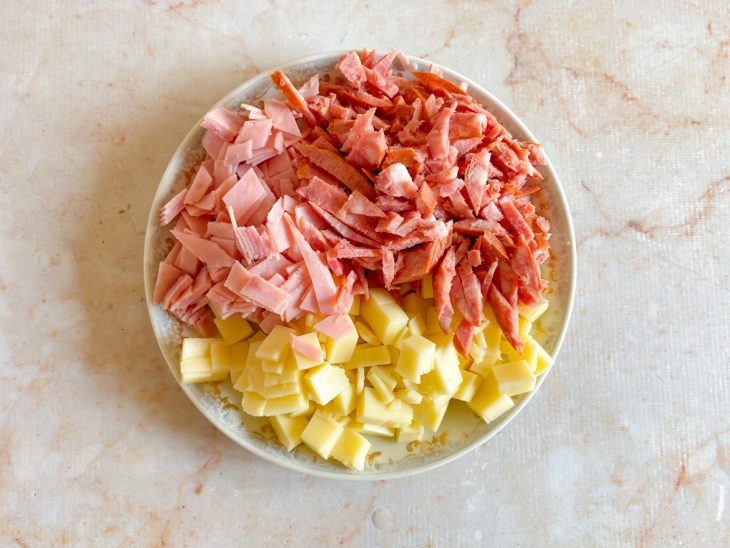 Calabresa, queijo e presunto picados em um prato.