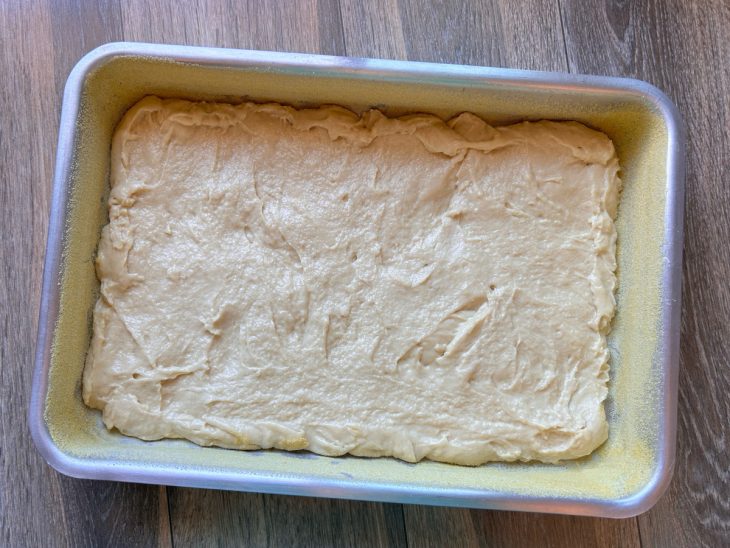 Massa acomodada em uma forma untada com margarina e fubá.