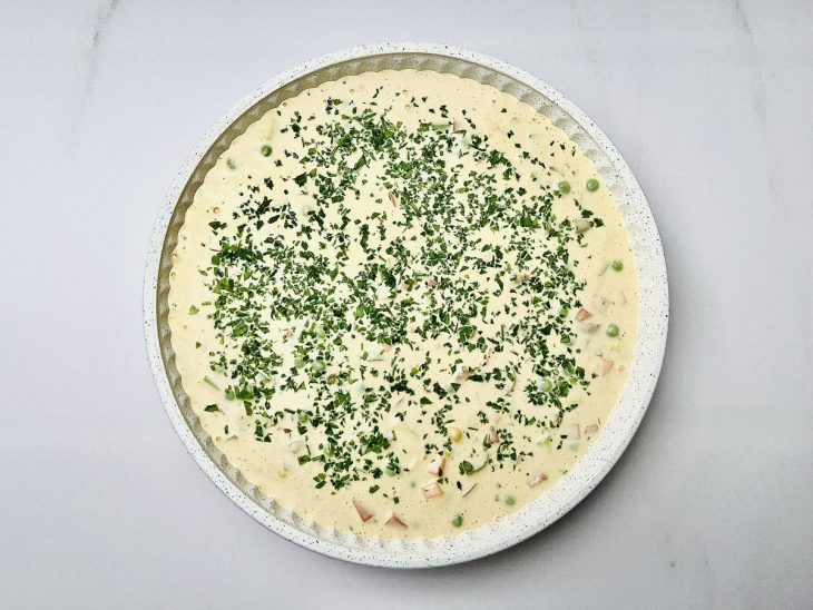 Mistura acomodada em uma forma untada com óleo vegetal e salsinha salpicada.