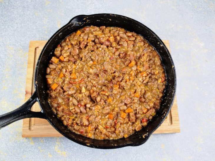 Caldo de feijão, farinha de mandioca e manteiga adicionados na frigideira com o restante dos ingredientes.