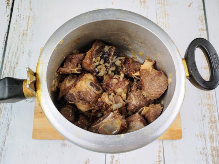 Cebola e alho adicionados na panela de pressão com costela bovina.