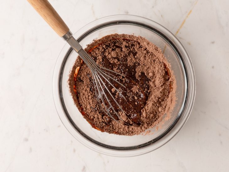 Tigela com chocolate em pó sendo dissolvido por água quente.