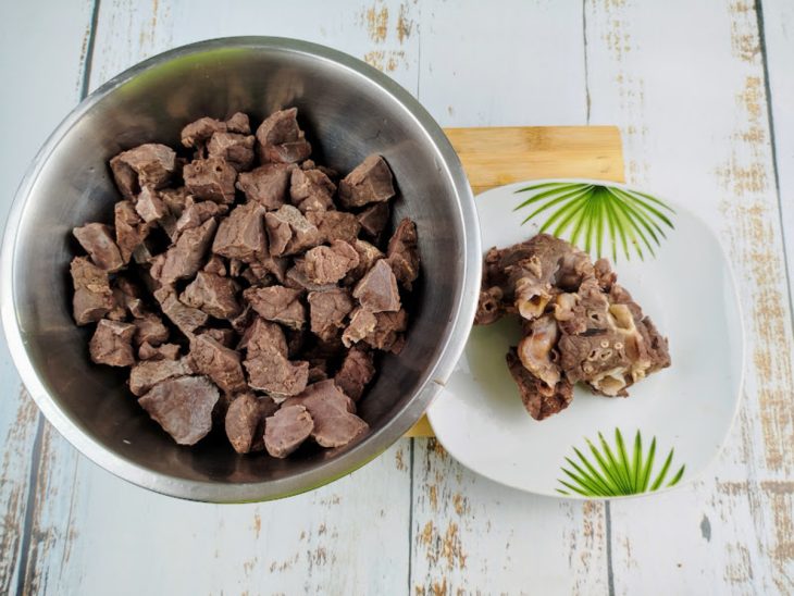 Carne de bofe cozido com um prato ao lado com canos e peles.