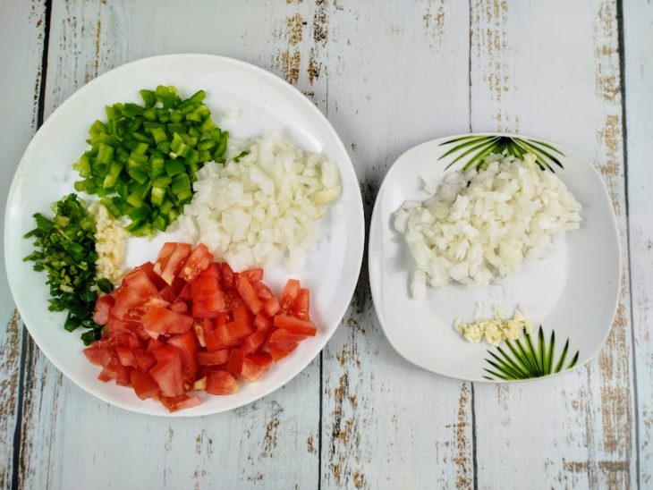 Tomate, pimentão, cebola, alho e coentro em dois pratos.