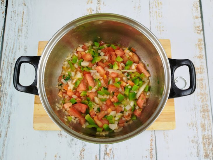 Cebola, alho, pimentão, tomate refogados em uma panela.