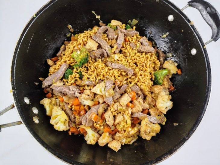 Uma panela com a mistura do macarrão, carnes, legumes e molho.