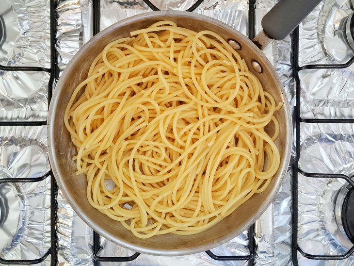 Macarrão cozido em uma frigideira com óleo.