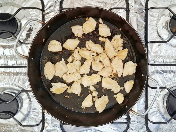 Cubos de frango em uma frigideira com óleo.